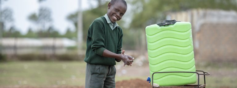 Smiling young boy African washing hands