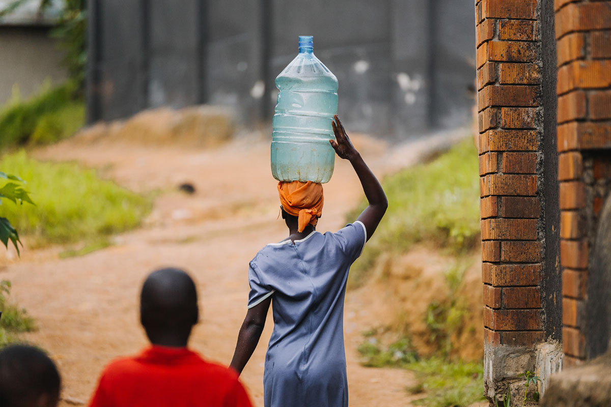 Afrikansk kkvinne fra Uganda bærer vann på hodet